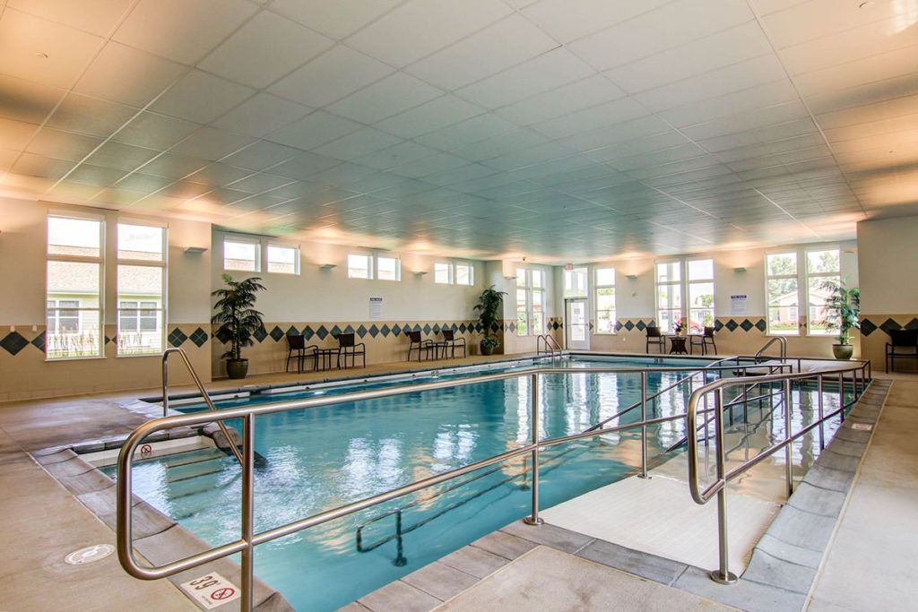 A spacious indoor swimming pool with surrounding railings and tiled floors.