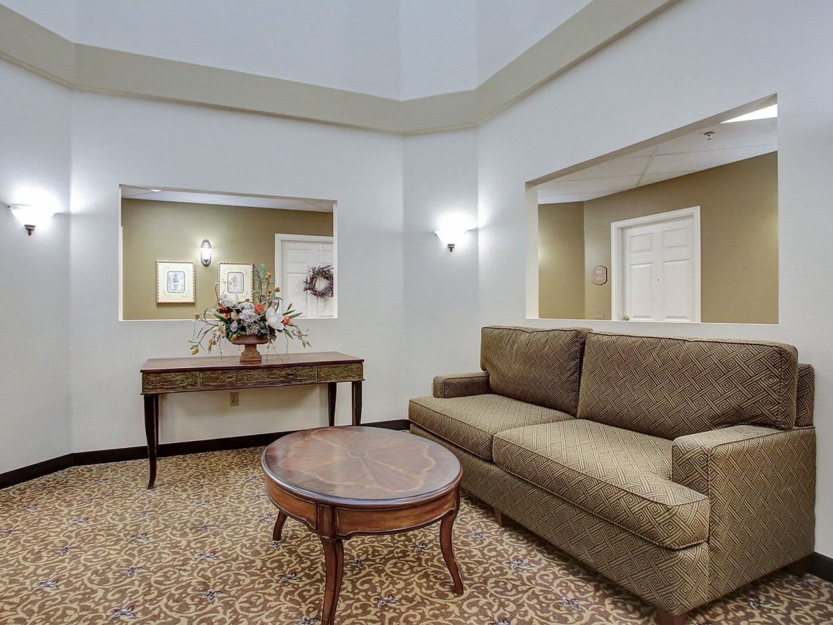 A cozy living room with a brown sofa, round coffee table, decorative console table, and wall mirrors.