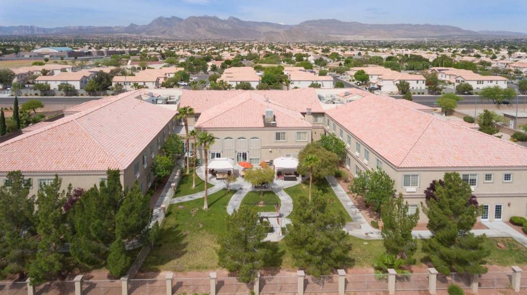 Aerial view of a residential neighborhood with gardens and mountain backdrop.