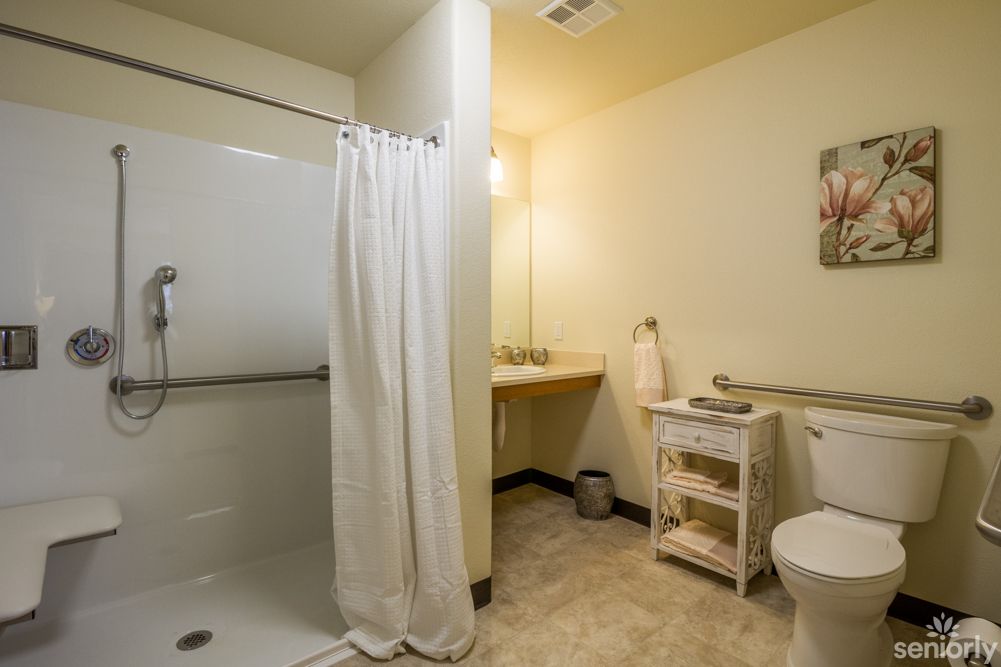A clean and organized bathroom with a shower, toilet, and sink.