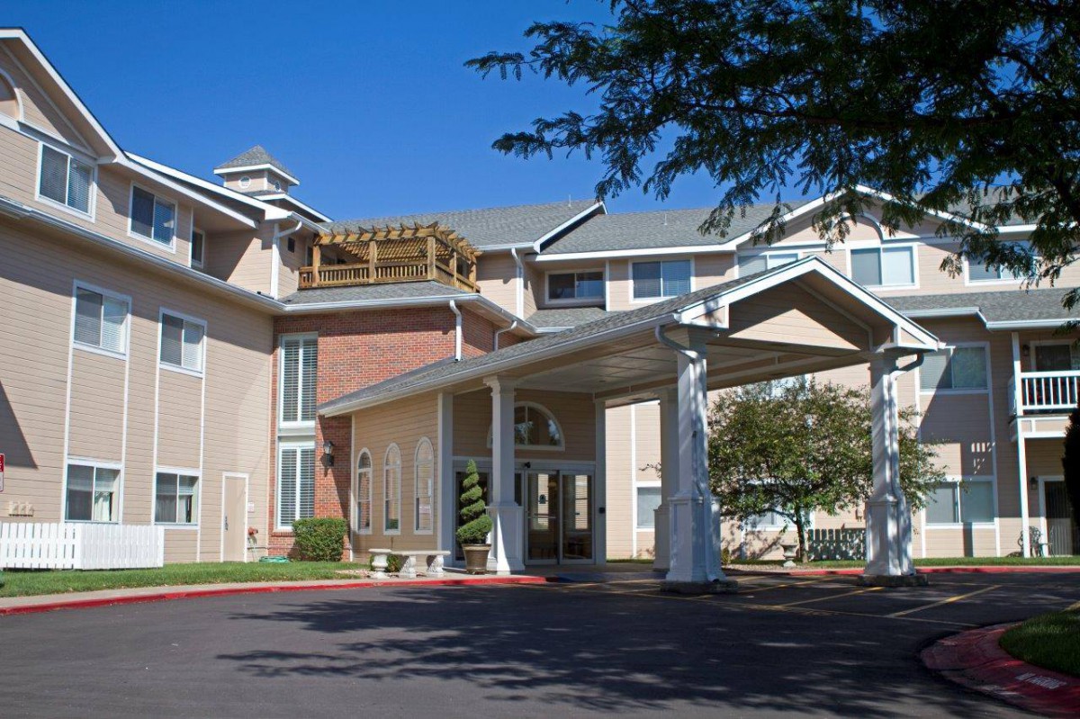 A residential building with a prominent entrance and covered driveway under a clear blue sky.