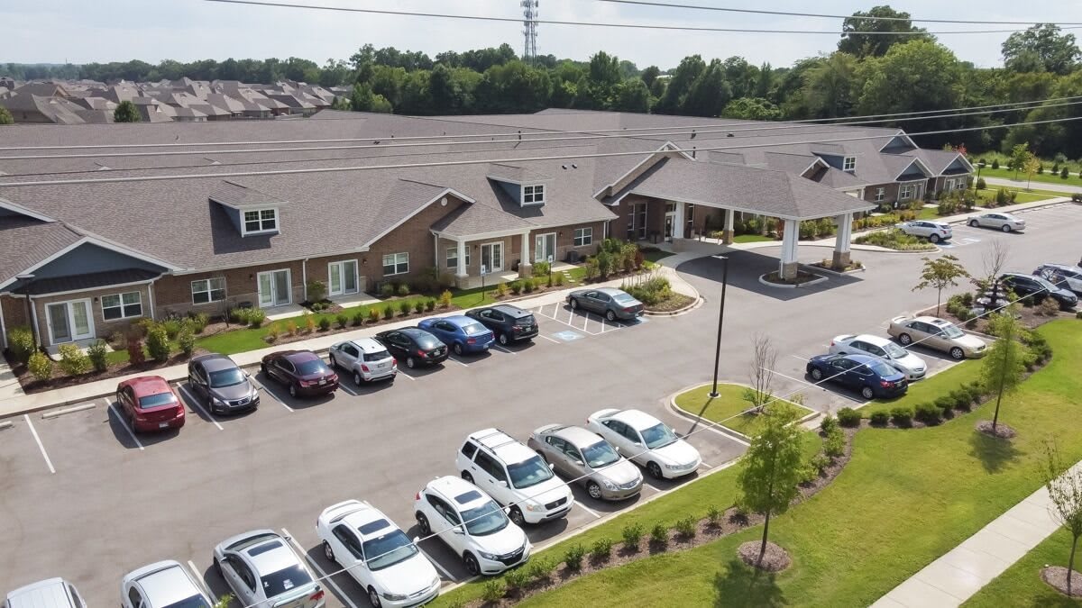 Aerial view of a residential building with a parking lot filled with cars in a suburban area.