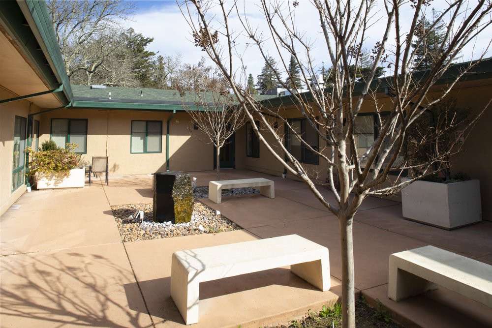 A serene courtyard featuring benches and leafless trees surrounded by a building.