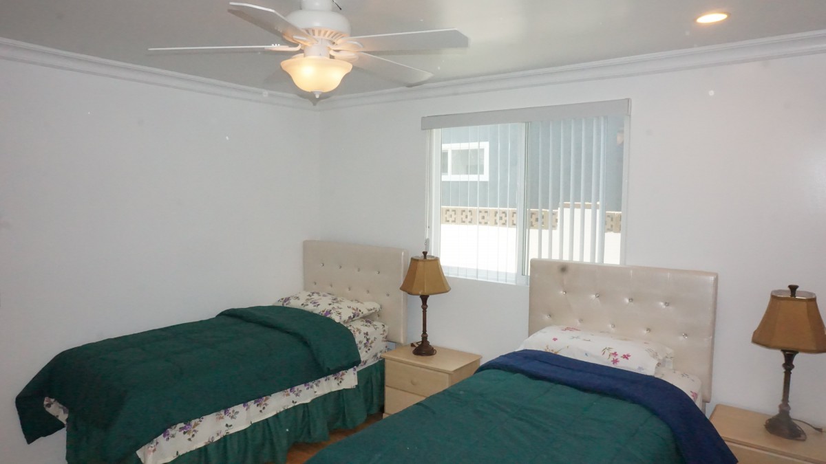A cozy bedroom with twin beds and a ceiling fan.