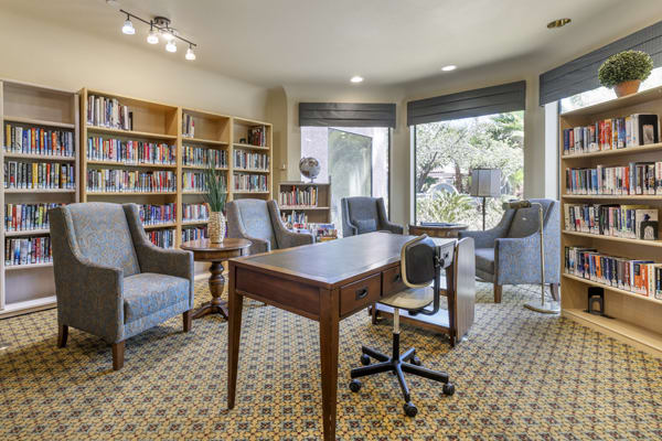 A cozy office library with bookshelves, a desk, and seating.