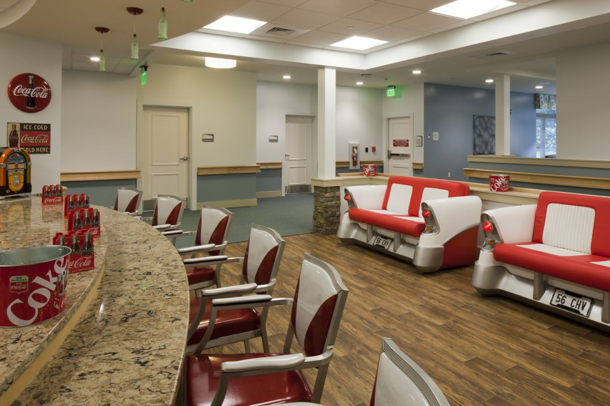 A well-lit, modern waiting area with red and white couches and chairs arranged neatly on a wood floor.
