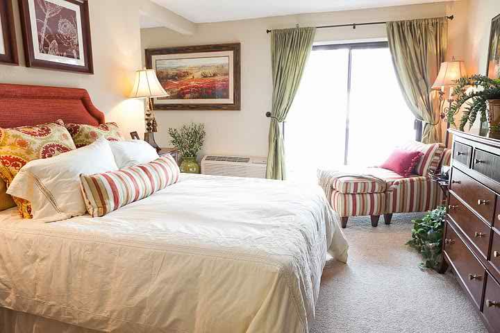 A cozy bedroom with stylish decor, featuring a comfortable bed, armchair, and elegant curtains.