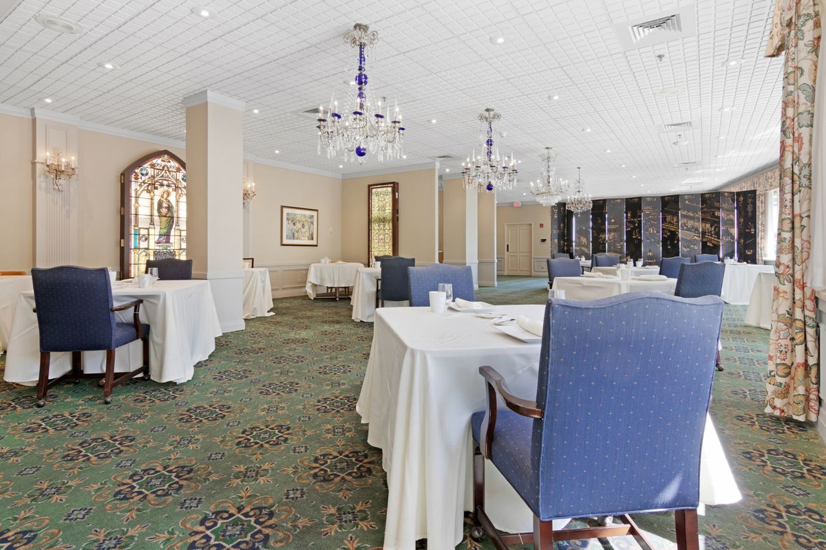 A spacious and elegantly decorated restaurant dining room with neatly arranged tables and chairs.