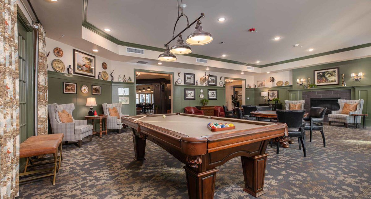 A stylish game room featuring a pool table and cozy seating area with elegant lighting.