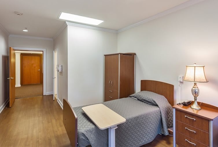 A hospital room with a single bed and essential furniture.
