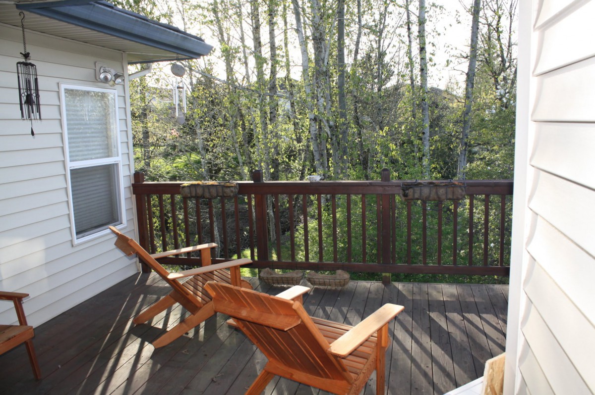 A peaceful deck with wooden chairs overlooking a lush forest.