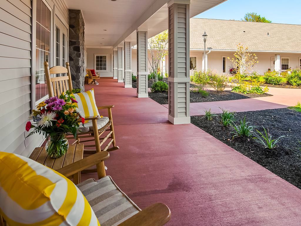 A welcoming porch with a rocking chair and vibrant flowers, perfect for relaxing outdoors.