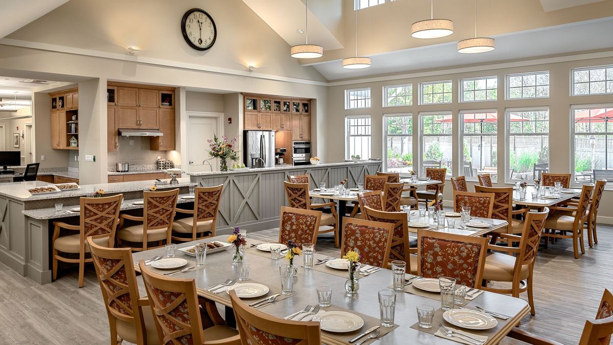 A well-lit dining room with neatly arranged tables and chairs, featuring large windows and a modern interior design.