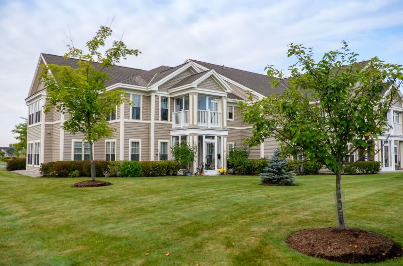 A spacious residential house with a well-maintained lawn and surrounding trees.