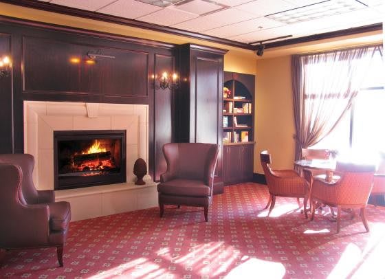 A cozy room with a fireplace, armchairs, and a table, creating a warm atmosphere.
