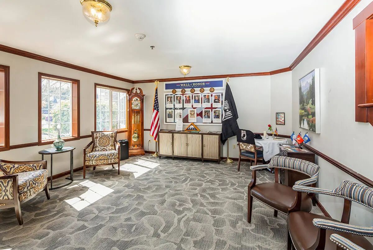 A well-lit office space featuring comfortable chairs, a grandfather clock, and wall decorations.