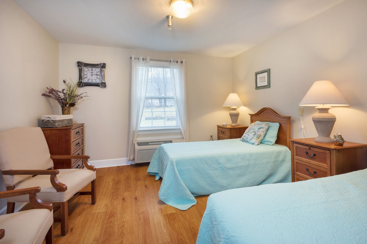 A cozy bedroom with two twin beds, adorned with light blue bedding and warm wooden furniture.