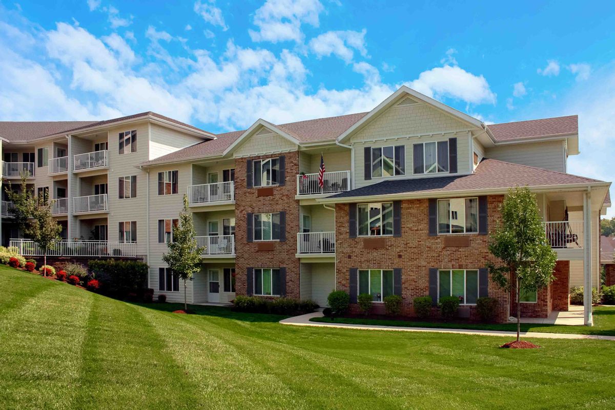 A modern apartment building with a well-maintained lawn under a clear blue sky.