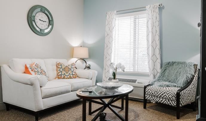 A cozy living room with a white couch, decorative pillows, and a round coffee table.