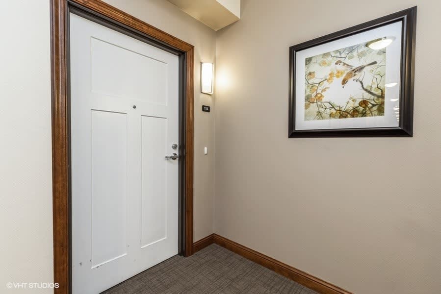 A hallway featuring a white door and framed artwork on the wall.