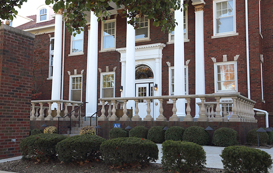 A historic building with large columns and a landscaped front.