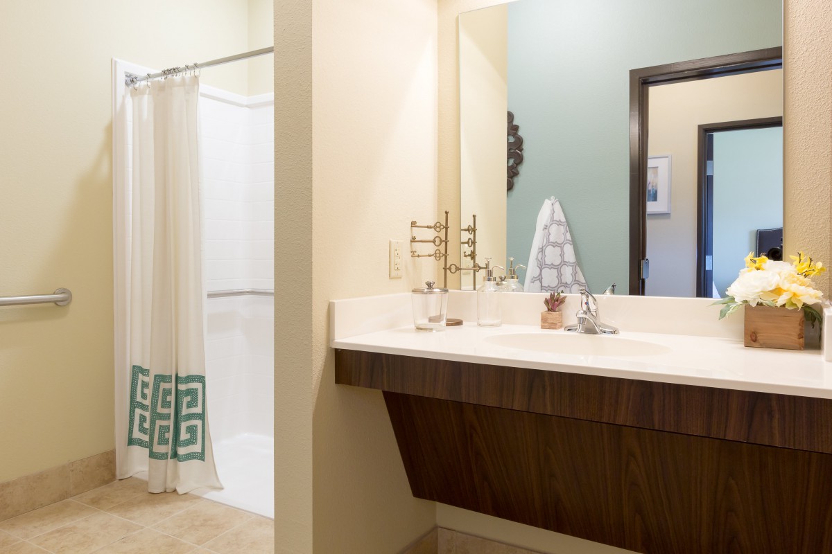 A modern bathroom with a spacious sink and mirror, featuring a shower area with a decorative curtain.