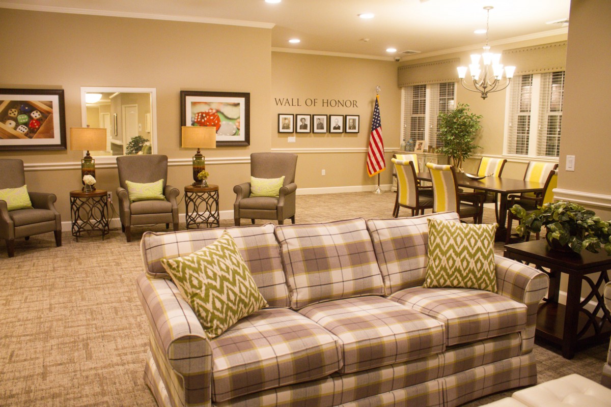 A cozy living room with a plaid sofa, elegant chandelier, and American flag decor.