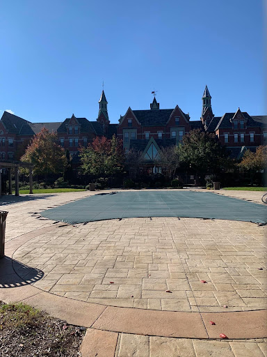 A sunny day at a scenic park featuring a large, covered area in front of an architectural structure.