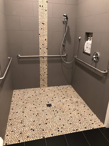 A spacious and modern accessible shower equipped with handrails and a textured tile floor.