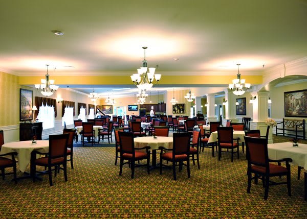 Elegant dining room with multiple tables and chandeliers.