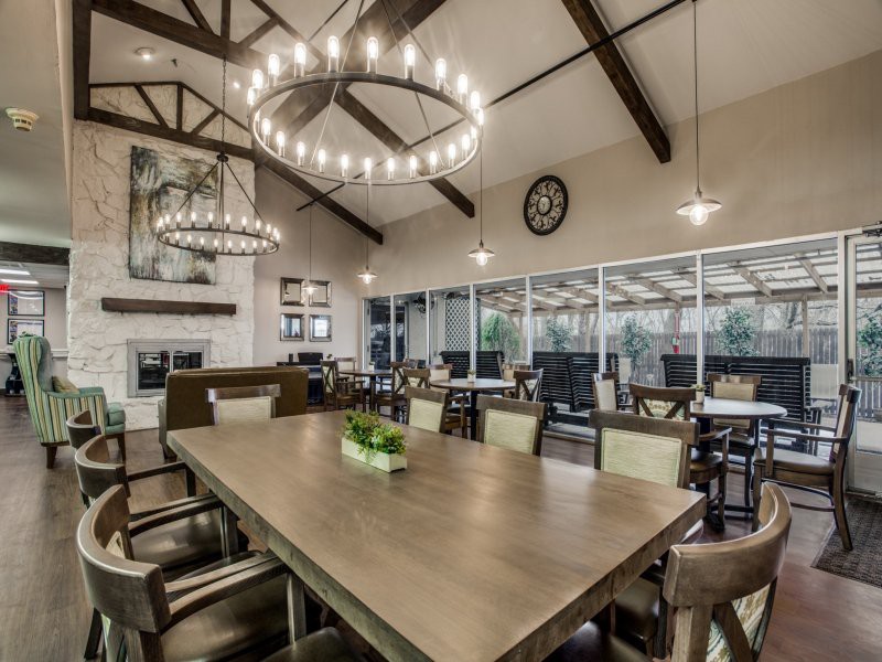 A spacious and modern dining room with a large wooden table, elegant chandeliers, and high ceilings.