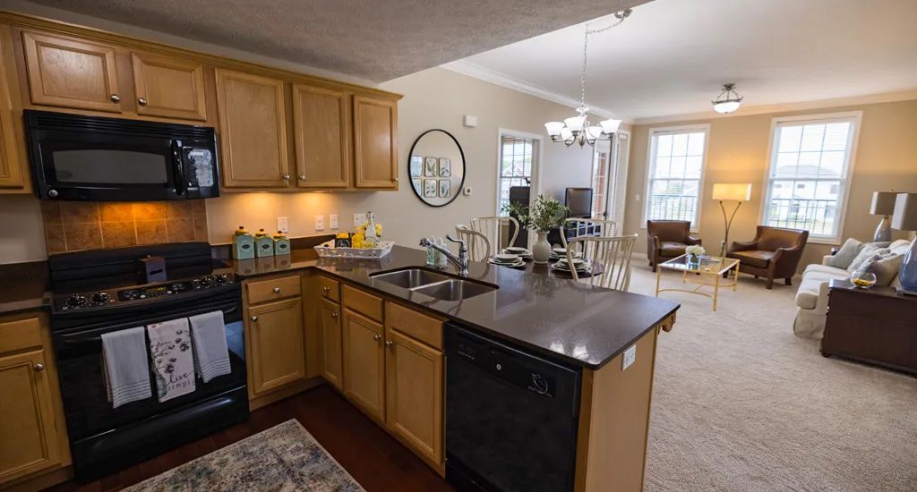 A modern open-concept kitchen with wooden cabinets, adjacent to a dining and living area.
