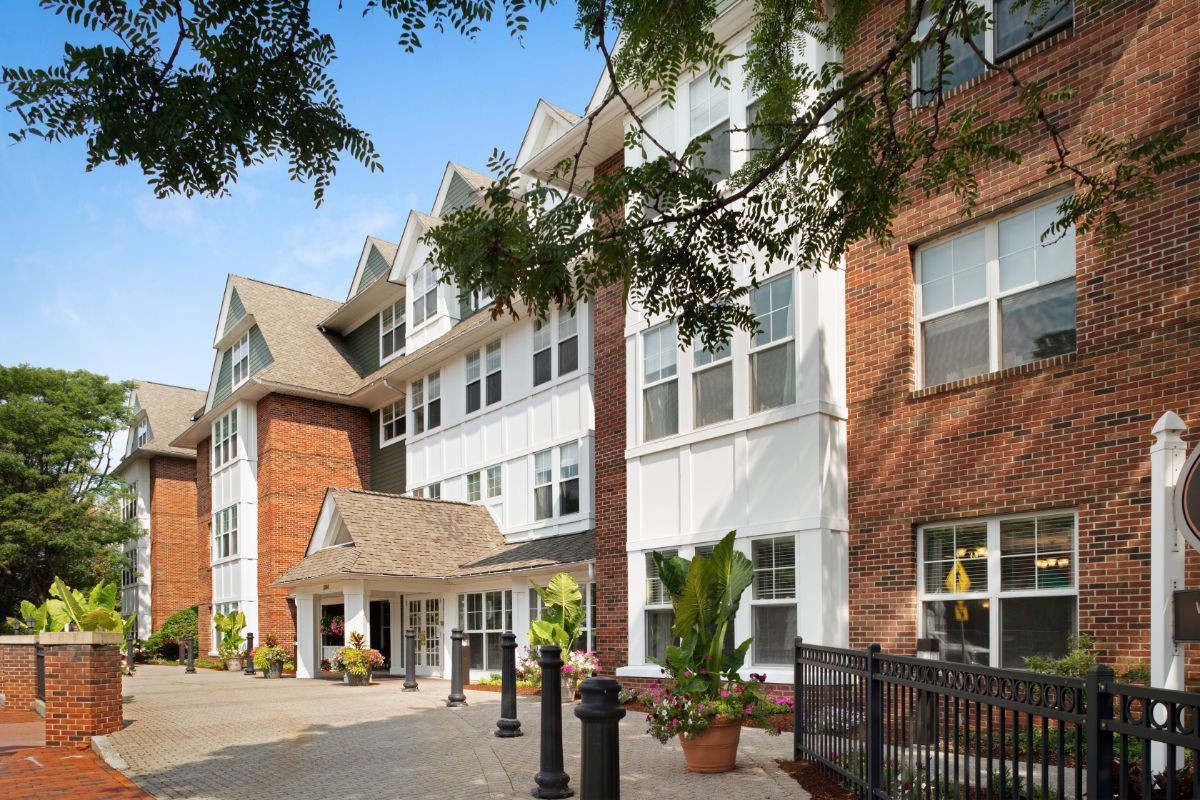 A multi-story residential building with a welcoming entrance, surrounded by trees.