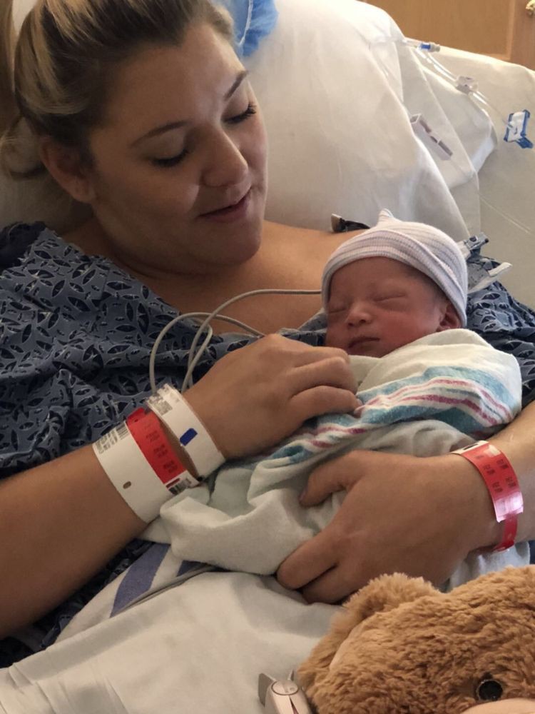 A mother holding her newborn baby in a hospital setting.