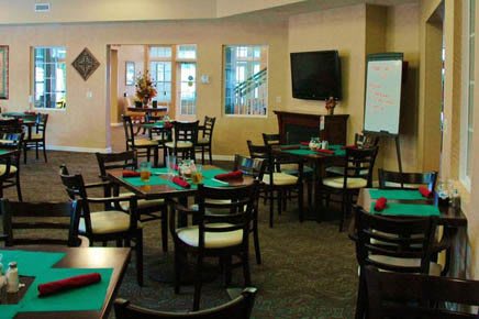 A cozy dining area with neatly arranged tables and chairs, a television, and a whiteboard.