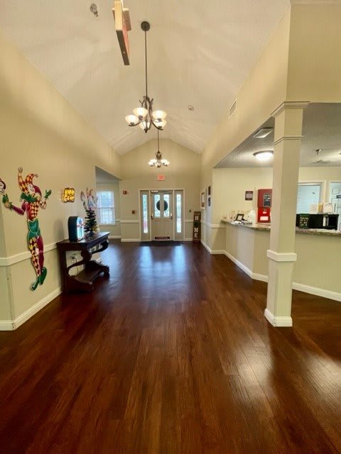 A spacious lobby with wood flooring, a chandelier, and colorful artwork on the wall.
