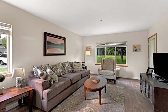 A cozy living room with a sofa, armchair, and coffee table by a window.