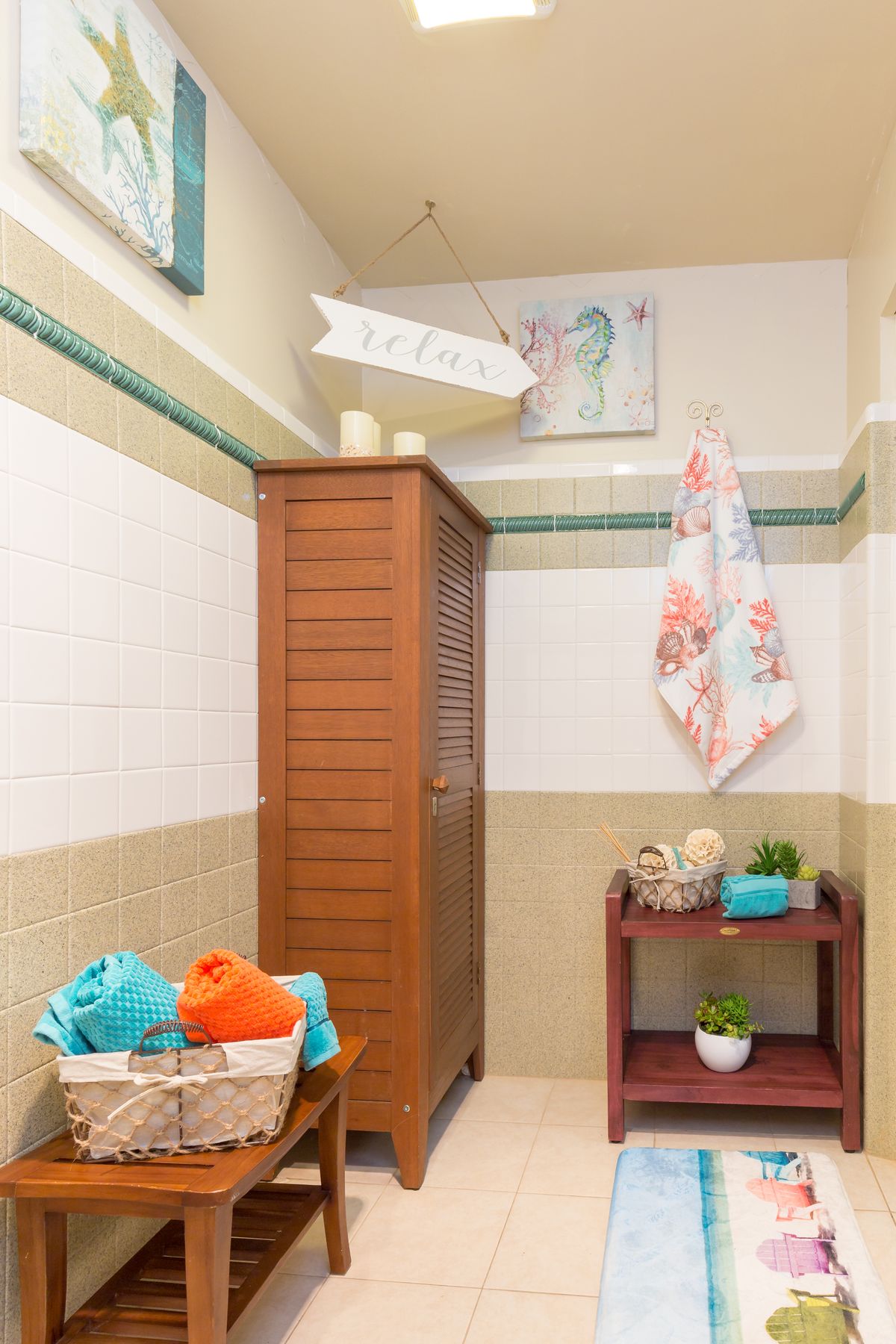 A neatly organized bathroom corner with a wooden cabinet, colorful towels, and decorative accents.