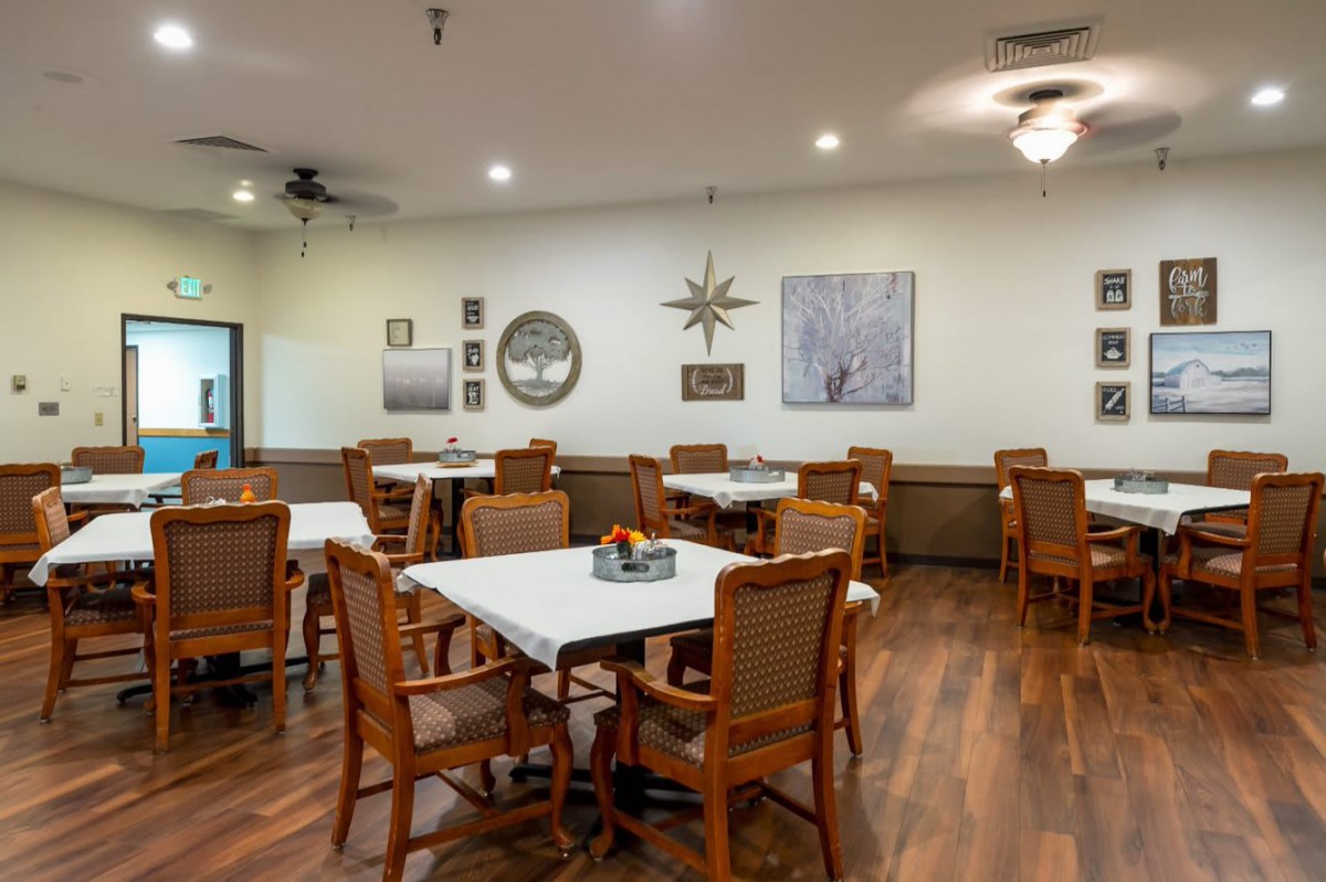 A cozy dining room with wooden tables and chairs, adorned with wall decor and a warm ambiance.