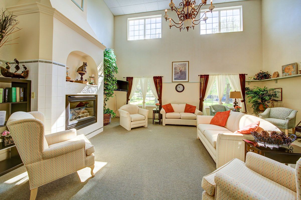 A spacious living room with elegant furnishings, featuring a fireplace, large windows, and a chandelier.