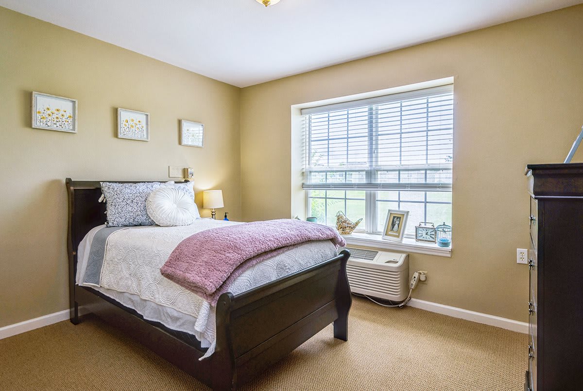 A cozy bedroom with a single bed, large window, and soft lighting.