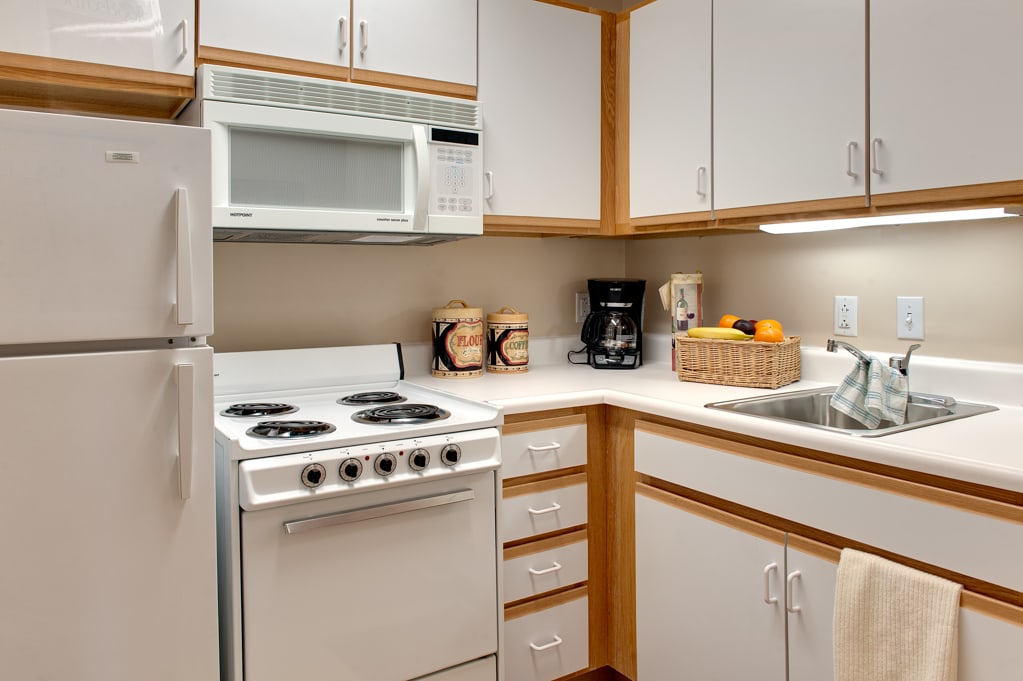 Compact kitchen with white appliances and wooden accents.
