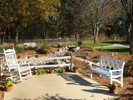 A tranquil garden setting with white benches and autumn foliage.