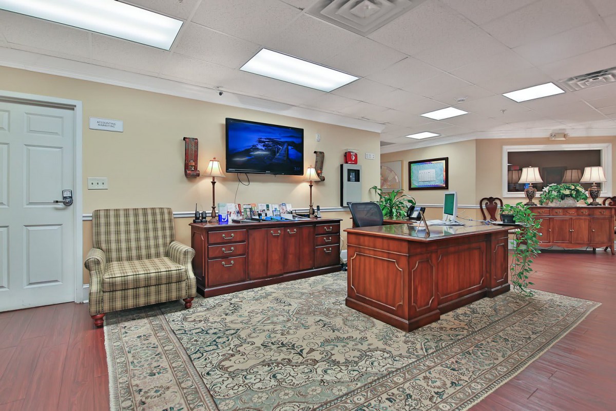 A cozy waiting room with an office desk and television.
