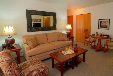 A cozy living room featuring a beige sofa, wooden coffee table, and warm lighting.