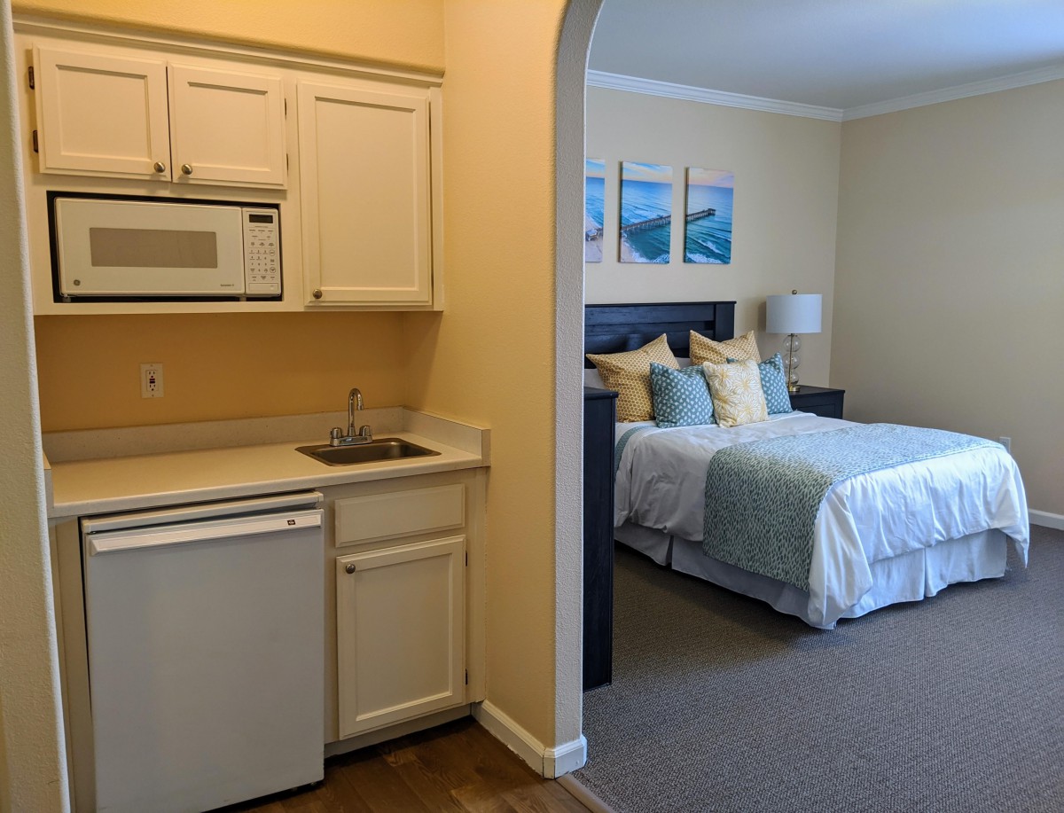 A cozy studio apartment with a kitchenette and a neatly arranged bedroom.