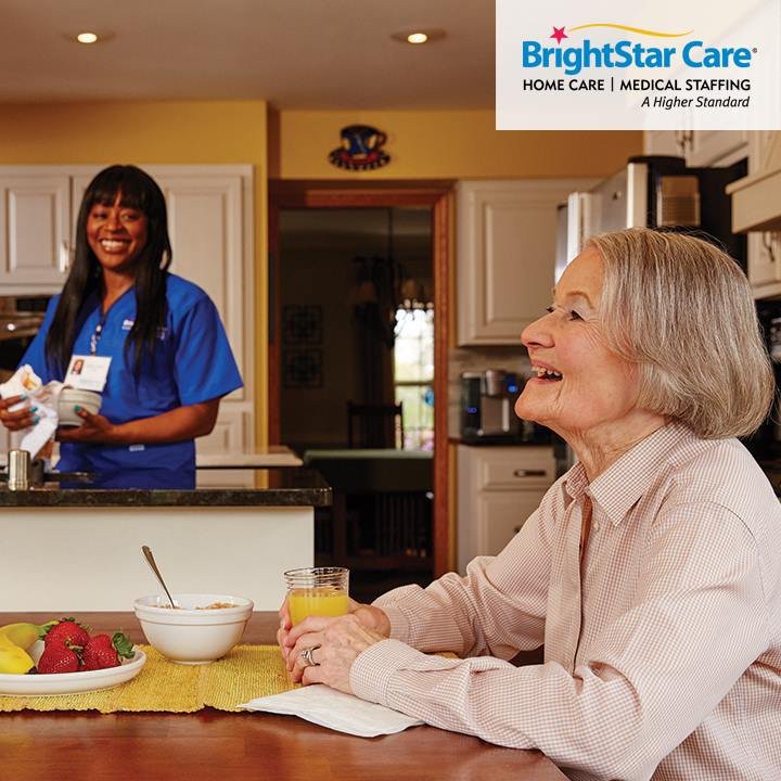 A caregiver assists an elderly woman in the kitchen, providing home care services.