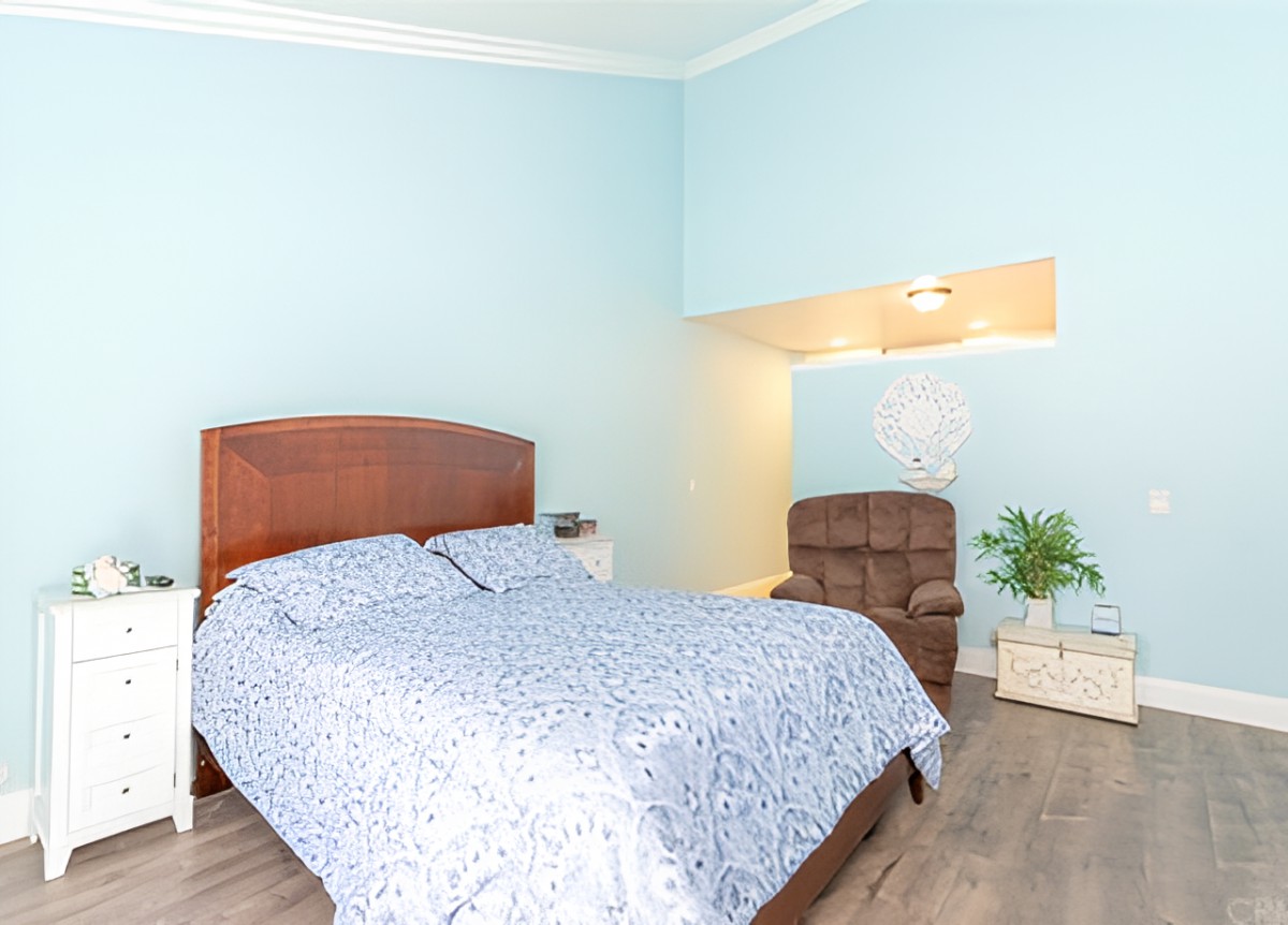 A cozy bedroom with blue walls, featuring a bed and an armchair.