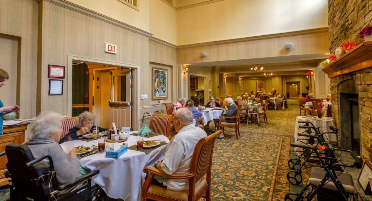 A cozy dining room with elderly people enjoying their meals.