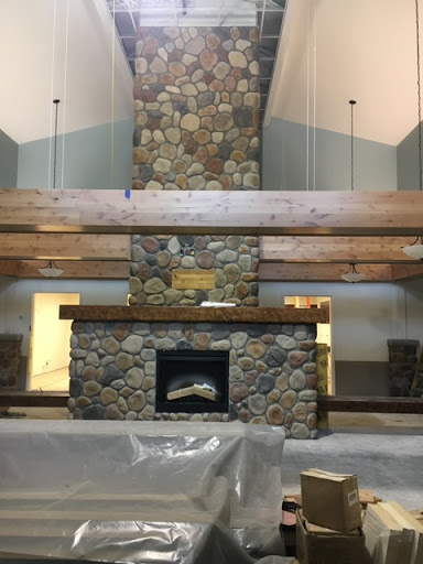 A beautifully designed interior space featuring a stone fireplace and wooden beams, showcasing a blend of natural materials and modern design.